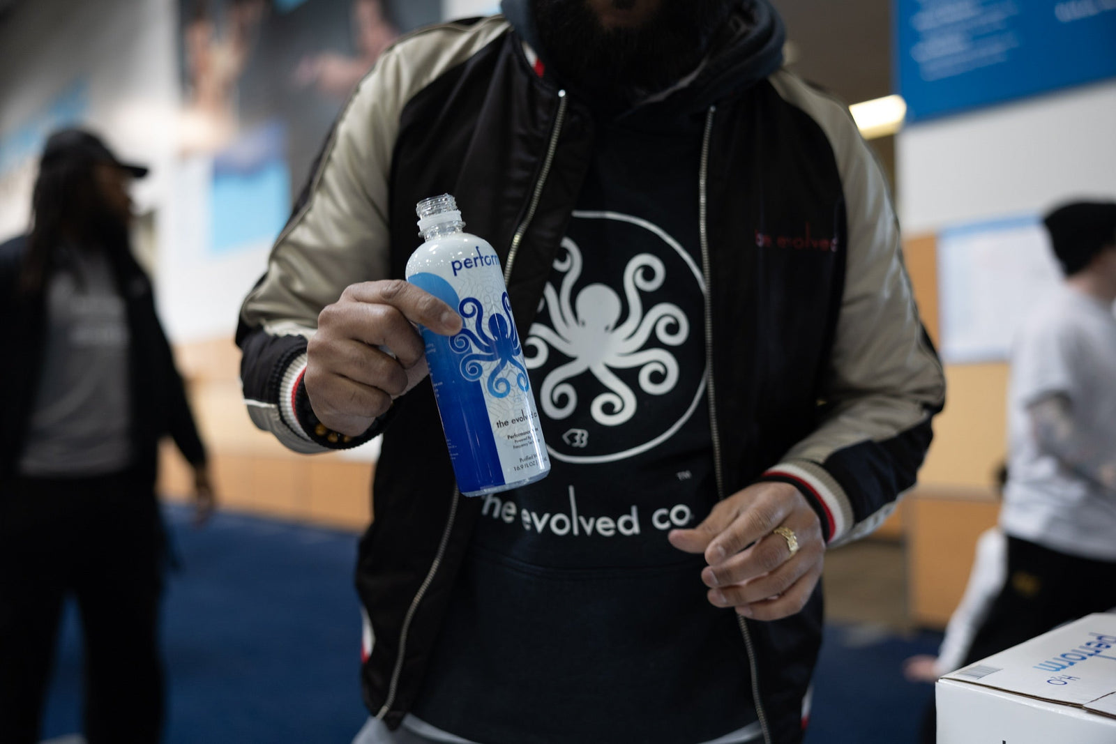 A man holding performH2O bottled water while wearing The Evolved Co gear